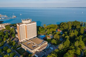 A high-rise hotel with a rooftop pool, surrounded by greenery and a marina with boats. - Danubius Hotel Marina (Balatonfured)