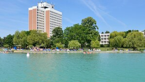 Un grand hôtel à plusieurs étages, doté d’une piscine et entouré de verdure.