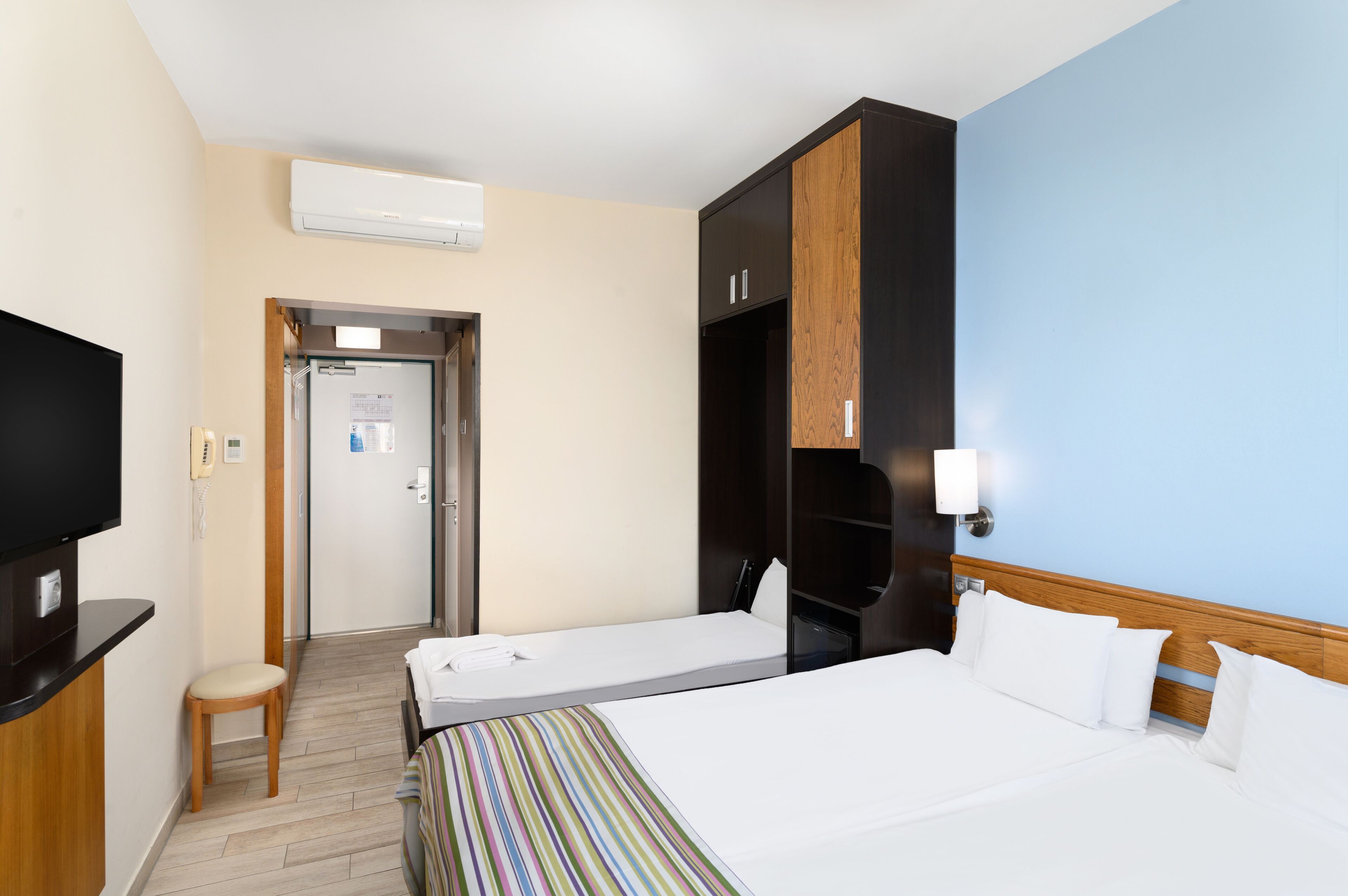 Een hotelkamer met een bed, een televisie, een bureau en een deur naar een badkamer.