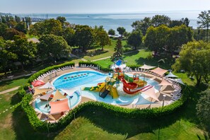 An aerial view of a resort with a large pool, water slides, and sun loungers. - Danubius Hotel Marina (Balatonfured)