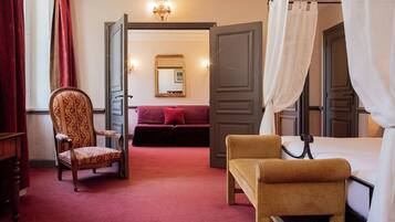 A hotel room with a bed, a chair, a sofa, and a mirror.
