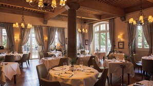Un restaurant avec des tables rondes, des lustres et de grandes fenêtres.