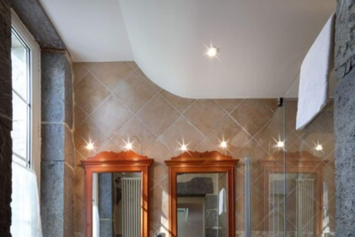 Un baño con dos lavamanos independientes, un box de ducha de vidrio y un espejo sobre cada lavamanos.