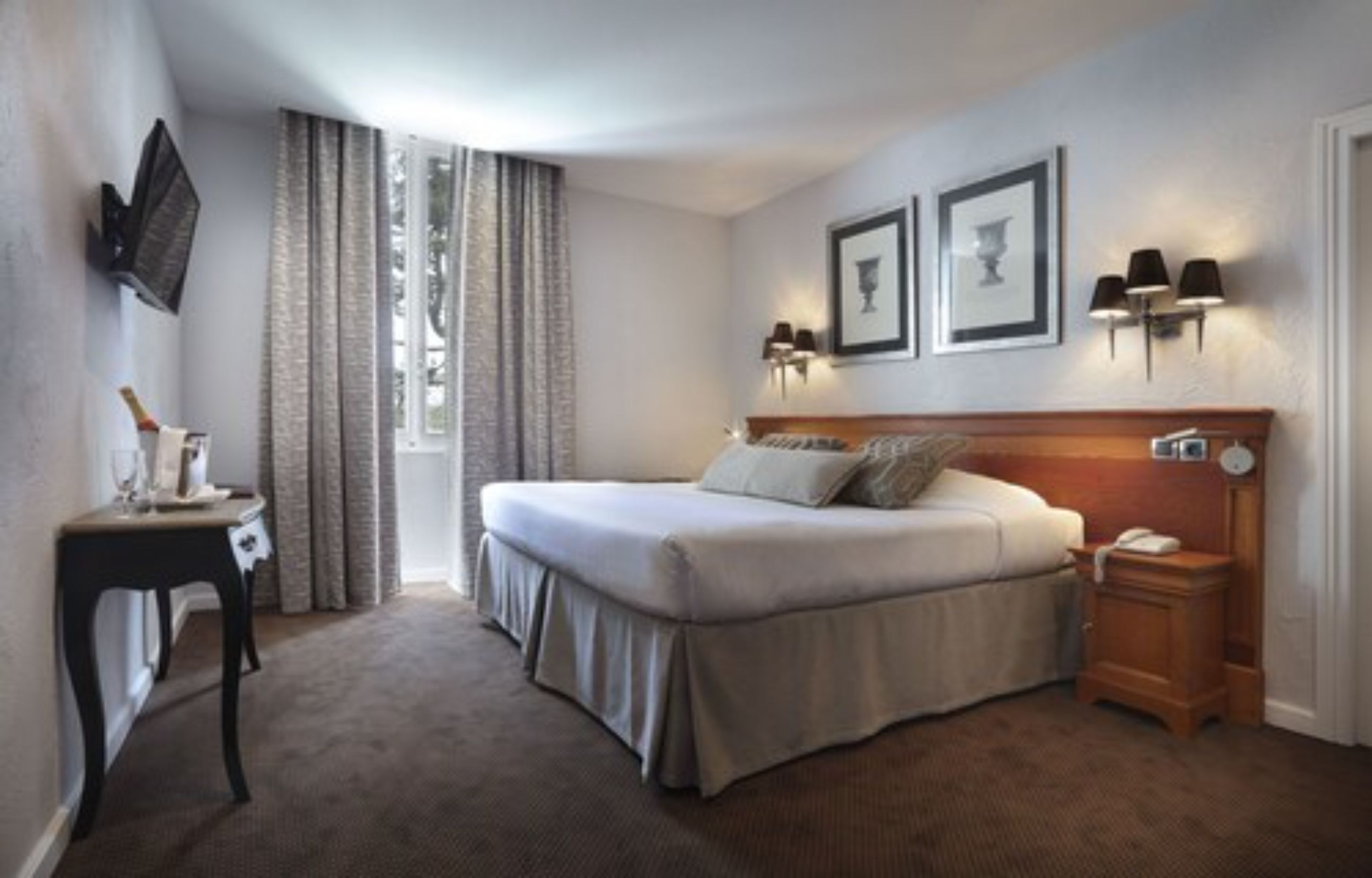 Une chambre d’hôtel équipée d’un lit, d’une table de chevet, d’une lampe et d’un téléviseur fixé au mur.