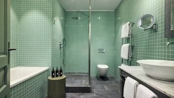 A bathroom with green tiled walls, a white toilet, a bathtub, and a sink with a mirror above it.
