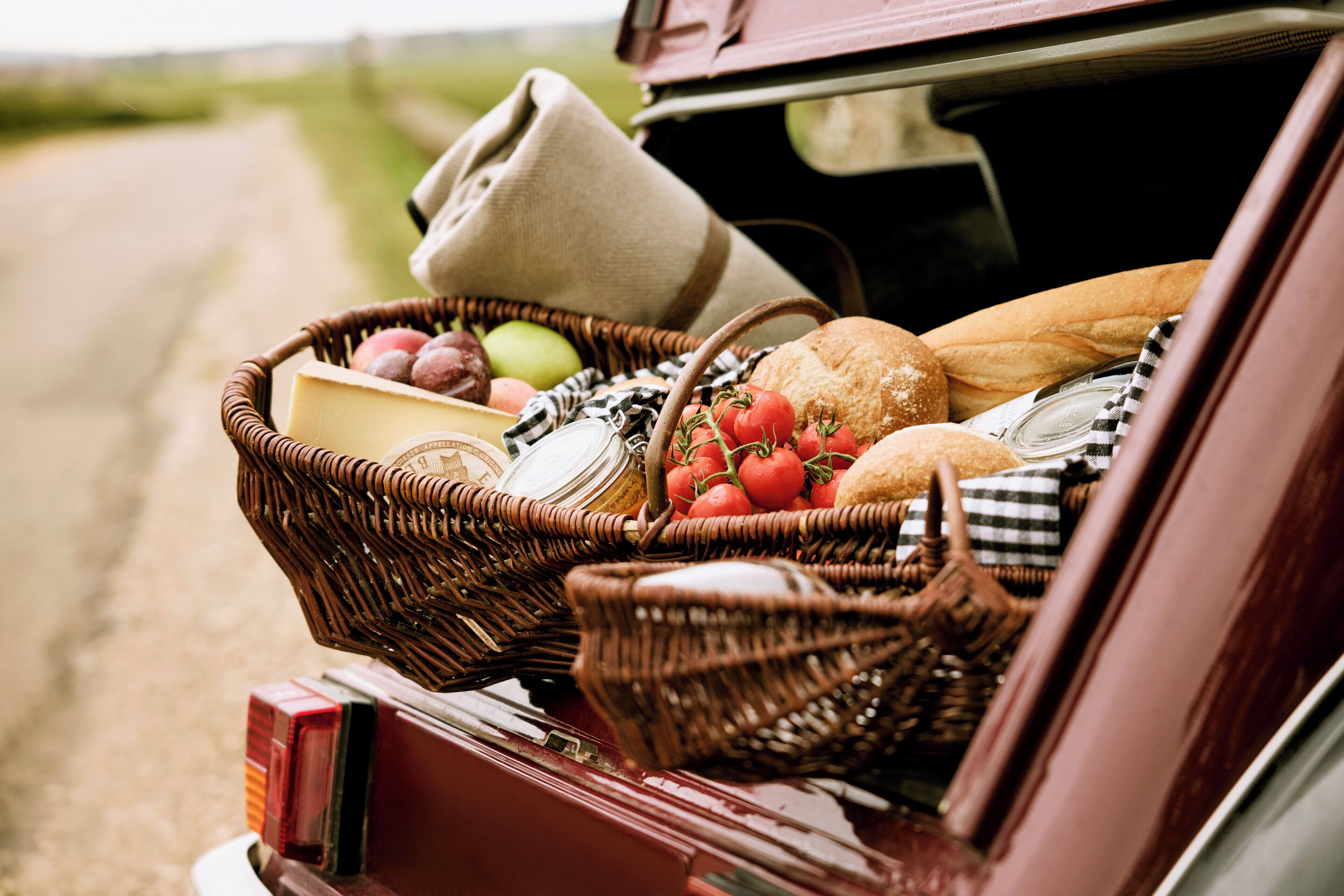 A wicker basket filled with food items in the trunk of a car.