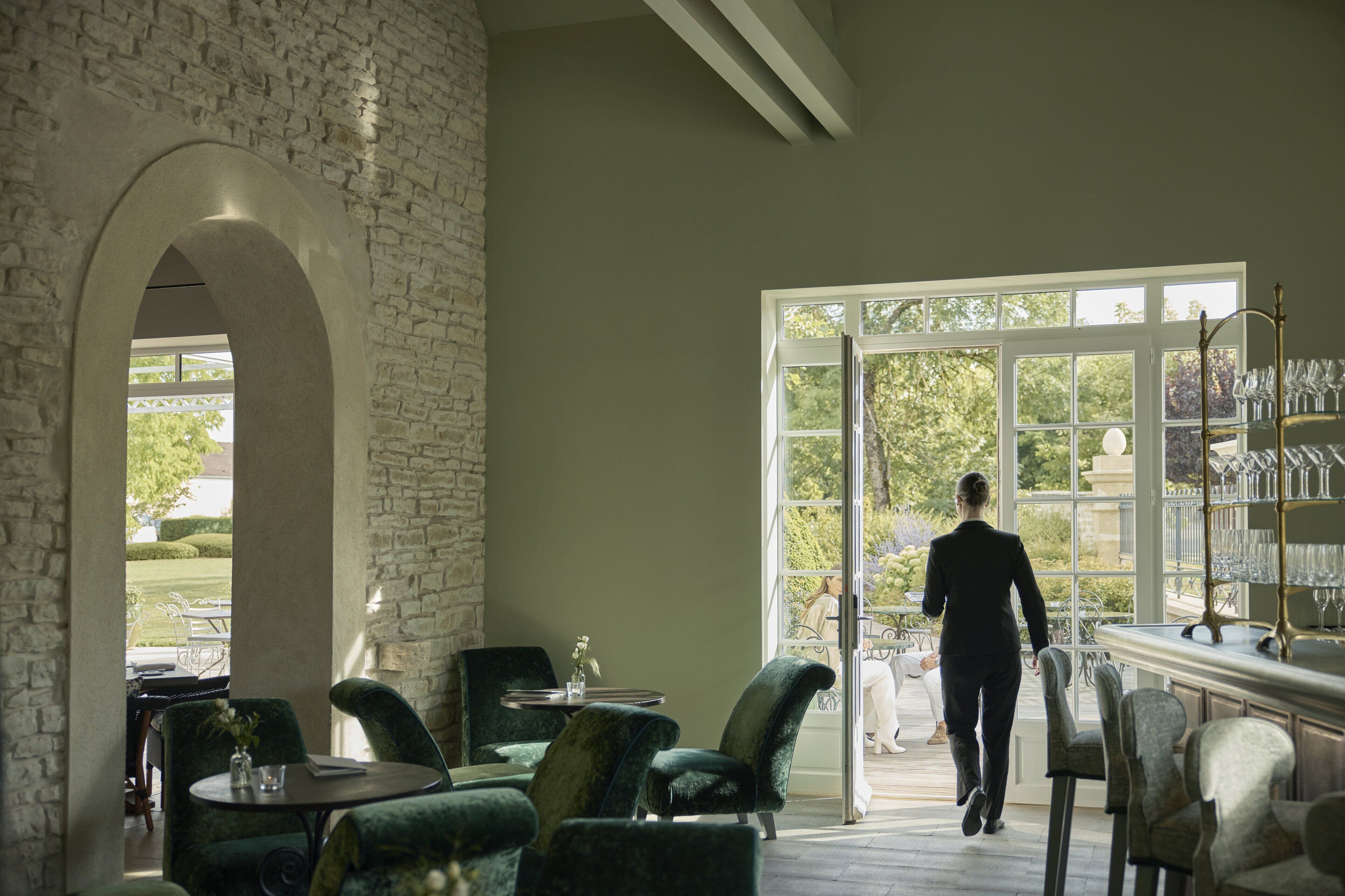 Una habitación amplia con un gran ventanal, una pared de piedra y una zona de bar con vasos.