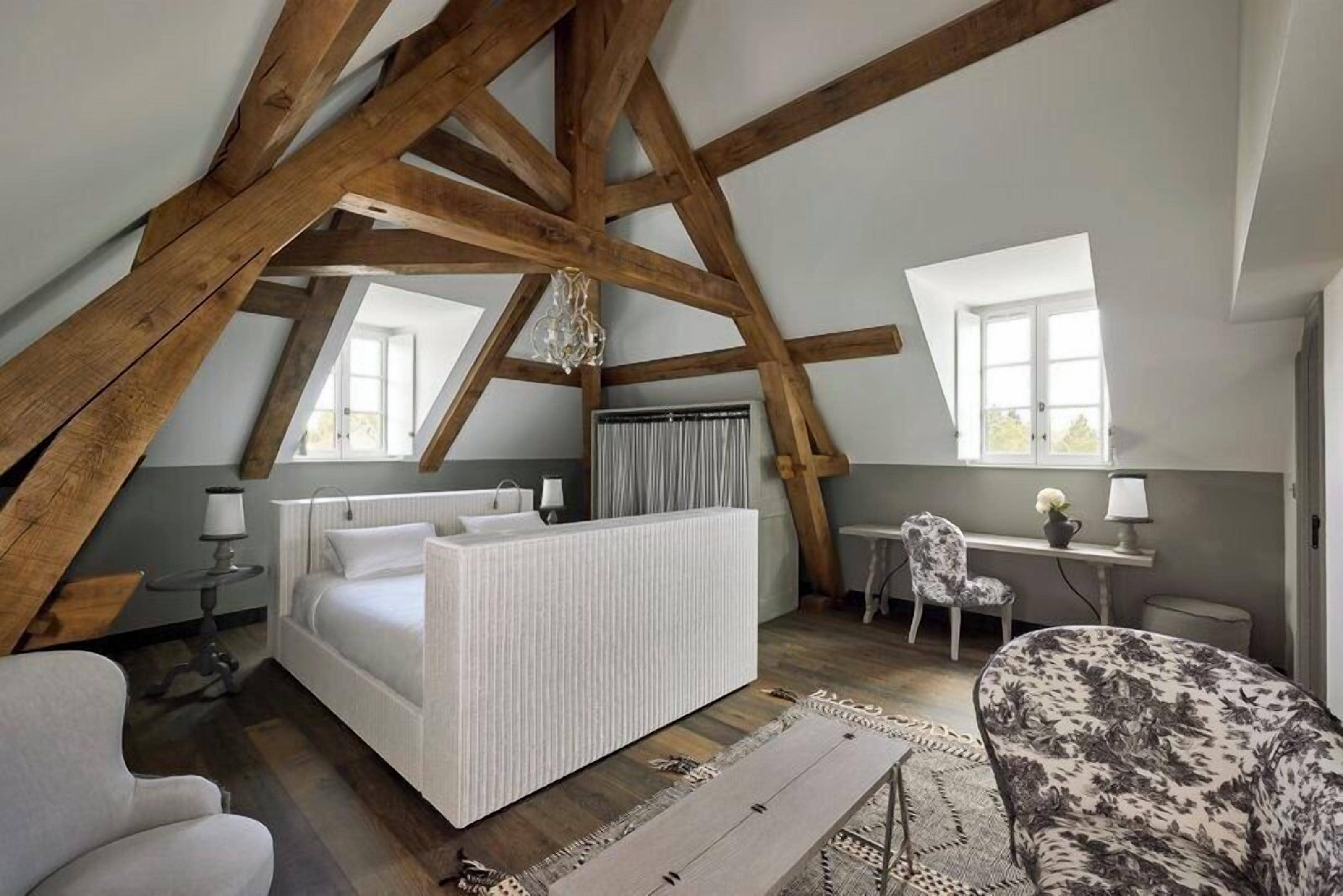 Ein Schlafzimmer mit schrägem Dach, einem Bett, einem Schreibtisch und einem Stuhl.