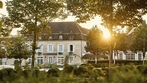 A stone building with multiple windows and a sign that reads "COMO LE MONTRACHET". - COMO Le Montrachet (Puligny-Montrachet)