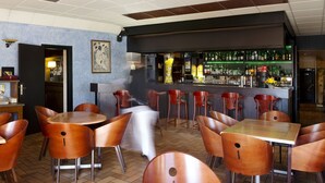 A bar area with a counter, stools, and a variety of bottles and glasses. - HOTEL Les Peyrières (Olemps)