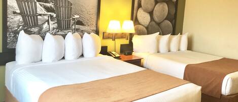 A hotel room with two beds, a painting of a beach scene, a lamp, and a telephone on the nightstand.