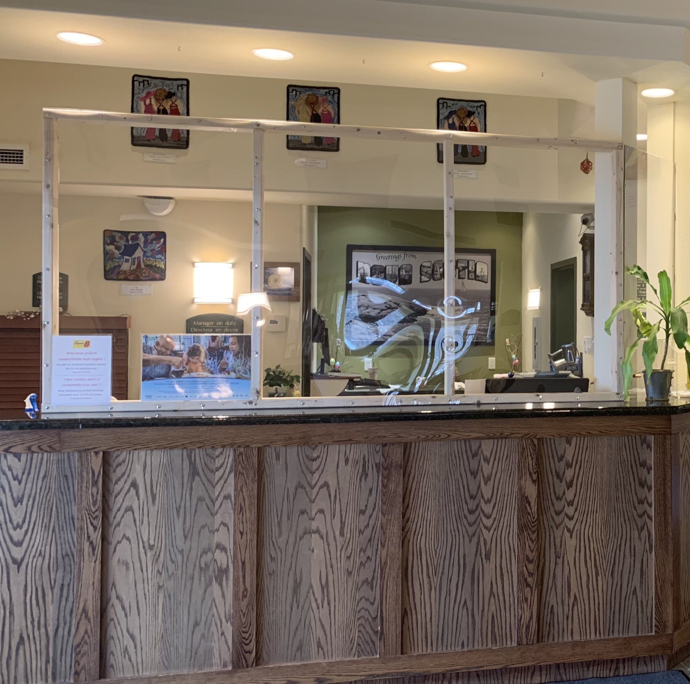 A reception desk with a wooden panel design, a glass partition, and various framed pictures on the wall.