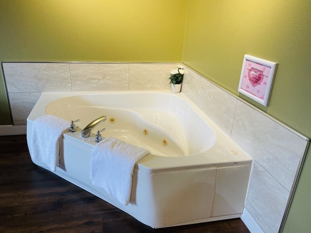 Une salle de bain moderne avec une baignoire sur pieds, une petite plante en pot et un tableau encadré au mur.