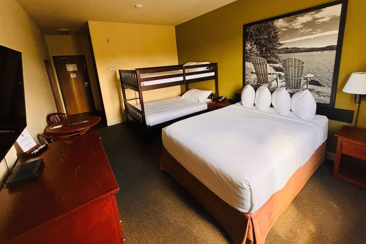 A hotel room with a large bed, a desk, a chair, and a television.