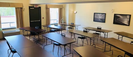 A conference room with multiple tables and chairs, a door marked "EXIT", and two windows with curtains.