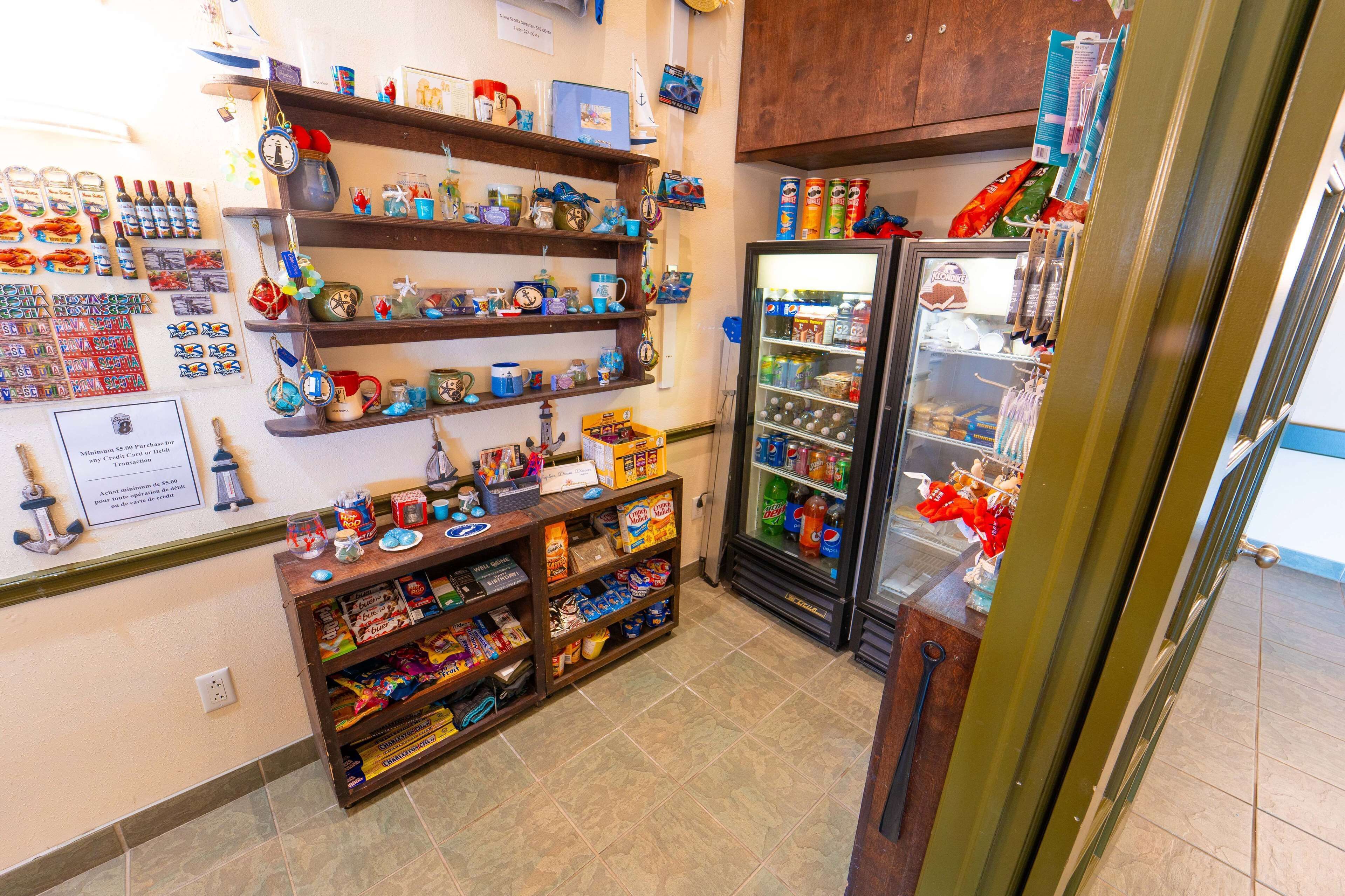 Uma loja pequena com prateleiras cheias de lembranças, um refrigerador abastecido com bebidas e uma exposição de diversos objetos na parede.
