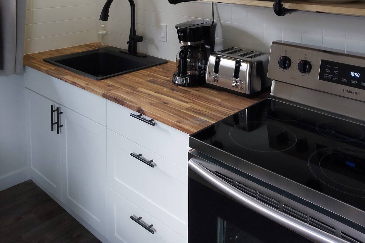 A kitchen with a sink, a coffee maker, a microwave, a toaster, and a stove.