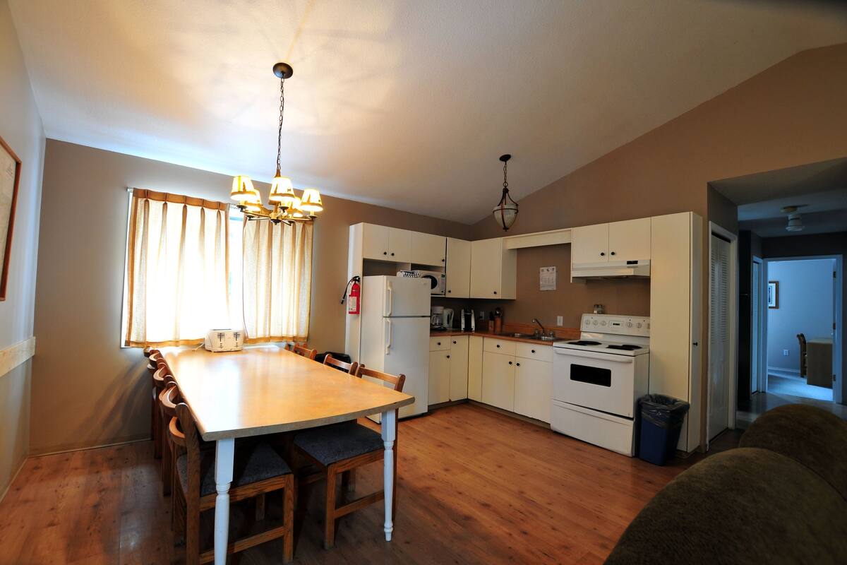 A compact kitchen with a dining table, white cabinets, and a stove.