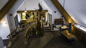 A wooden staircase with a unique spiral design, leading to a reception area with a wooden desk and a hanging bird sculpture. - Manning Park Resort (Manning Park)