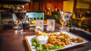 A dining table with a plate of fried food, a bowl of dipping sauce, and several glasses of water and wine. - Manning Park Resort (Manning Park)