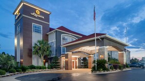 Een La Quinta hotel met een modern design, met een opvallende ingang, een vlaggenmast en verzorgde beplanting.
