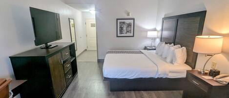 Hotelkamer met een bed, een televisie, een dressoir, een nachtkastje met een lamp en een lijst aan de muur.