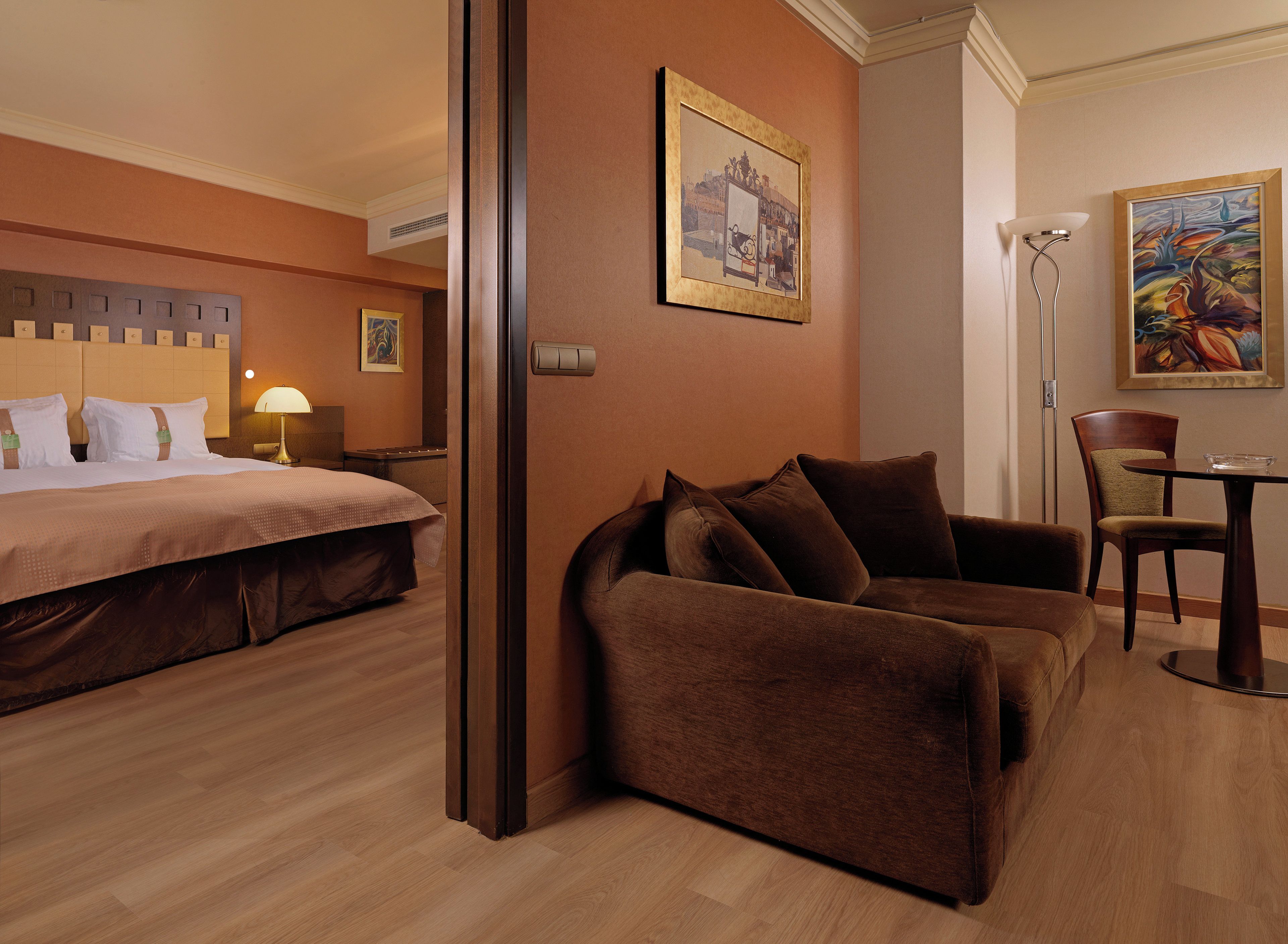 Ein Hotelzimmer mit einem Bett, einem Sofa, einem Esstisch und zwei Bildern an den Wänden.