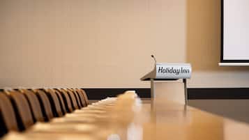 A piano with a sign reading 'Holiday Inn' in front of a wall with a projection screen.