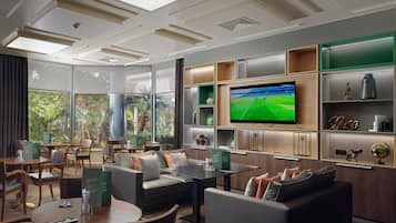 A modern hotel lobby with a flat-screen TV, comfortable seating, and a view of the outdoors.