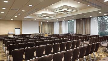 A conference room with rows of chairs, a projector screen, and a podium.