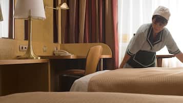Una habitación de hotel con una cama, un escritorio con lámpara, un teléfono y una silla.