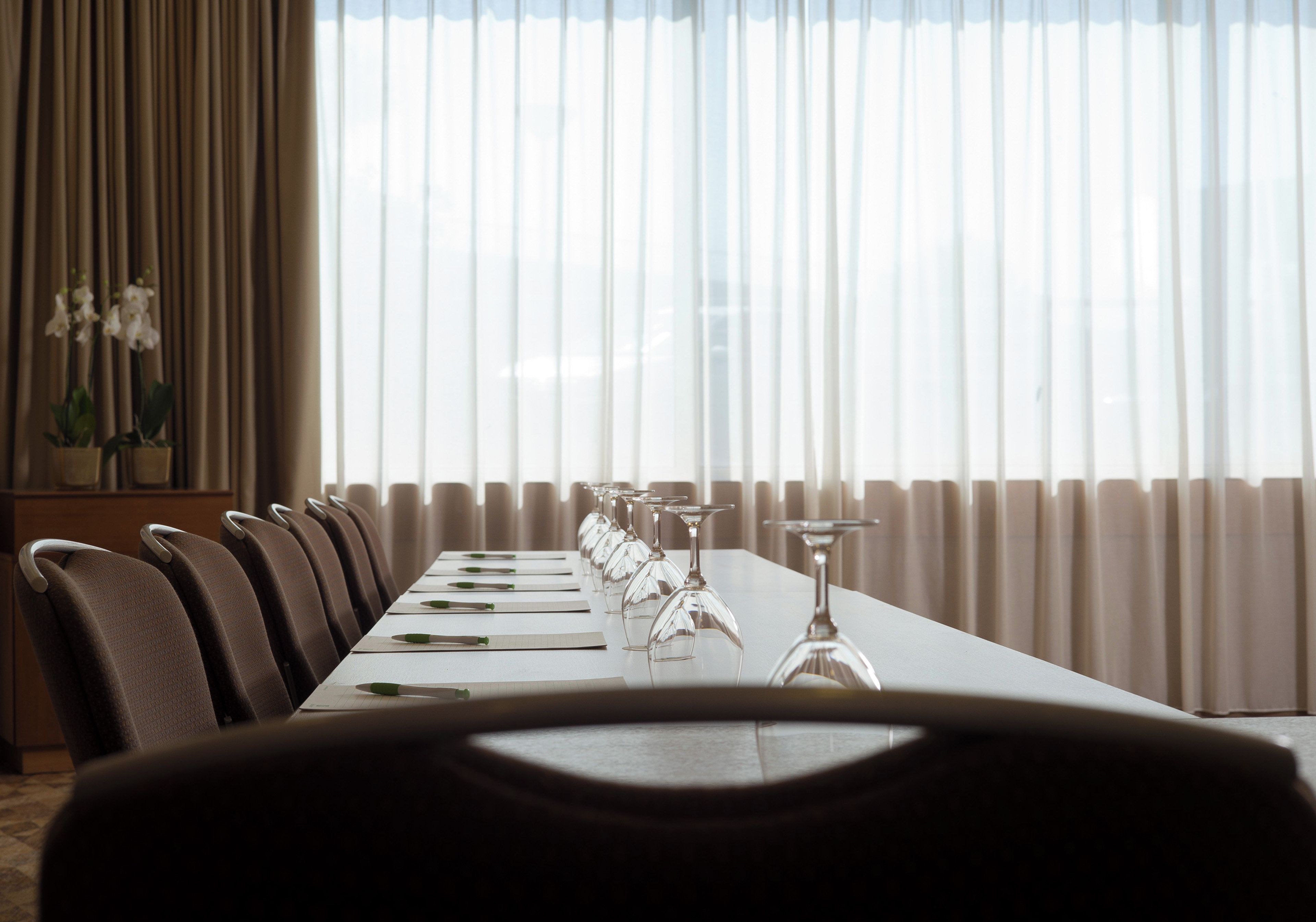 A conference room with a long table, chairs, and wine glasses.
