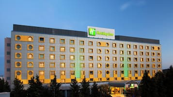A Holiday Inn hotel building with a modern facade, multiple windows, and a prominent green logo.