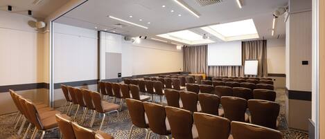 A conference room with rows of chairs, a projector screen, and a large window.