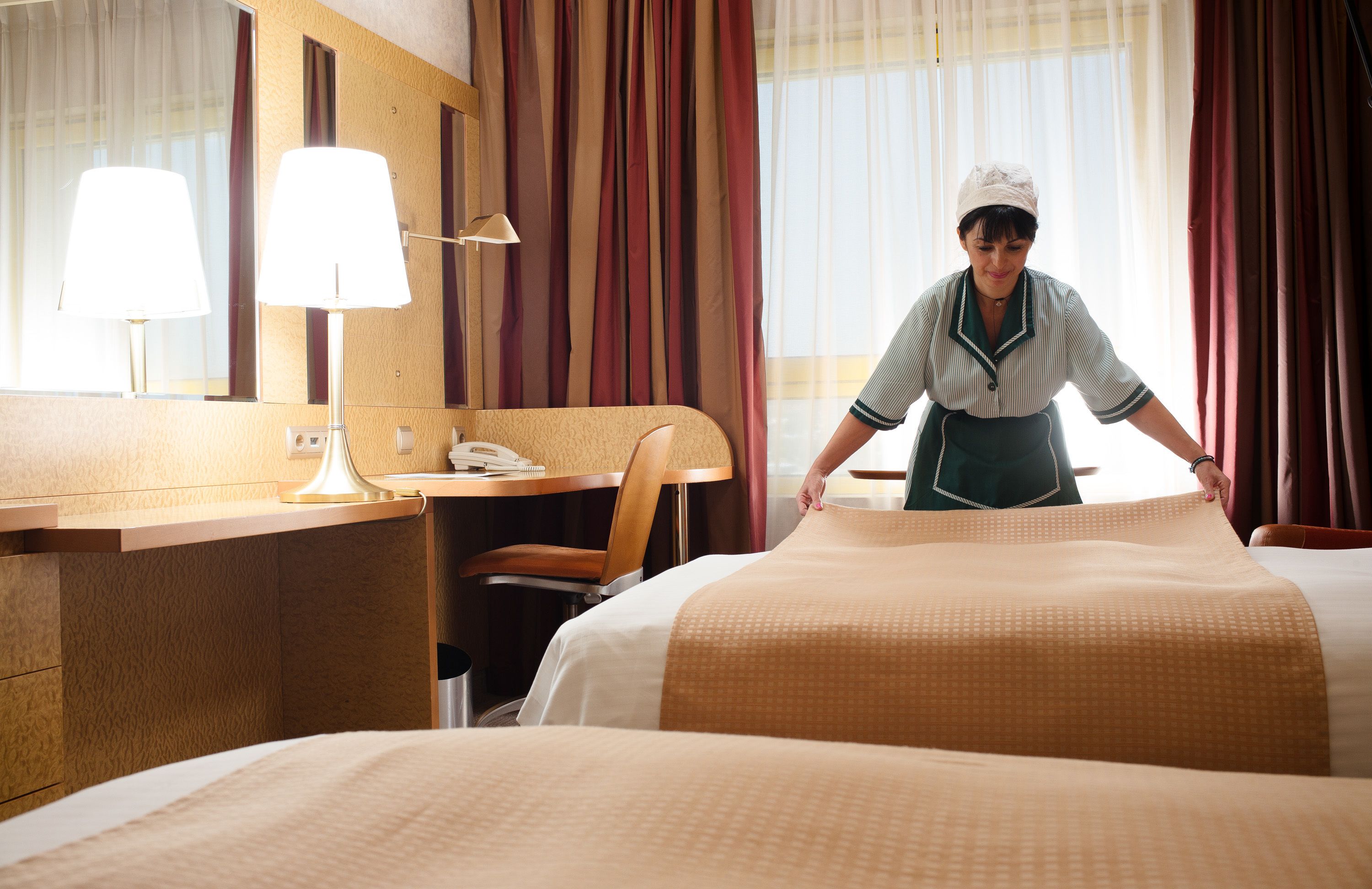 Ein Hotelzimmer mit Bett, Schreibtisch mit Lampe, Stuhl und Spiegel.