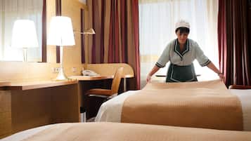 Ein Hotelzimmer mit Bett, Schreibtisch mit Lampe, Stuhl und Spiegel.
