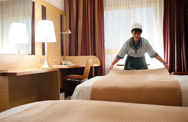 A hotel room with a bed, a desk with a lamp, a chair, and a mirror.
