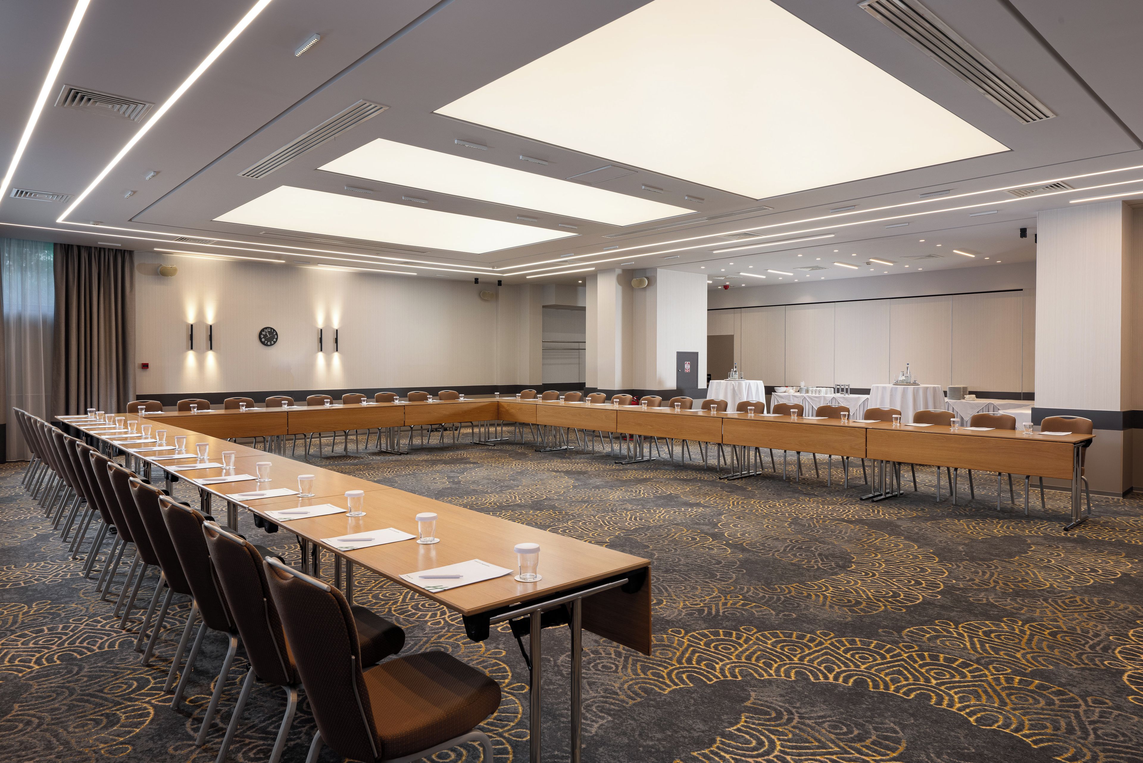 A conference room with a long table, chairs, and a carpeted floor.