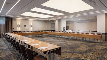 Un salón de conferencias con una larga mesa, sillas y suelo alfombrado.