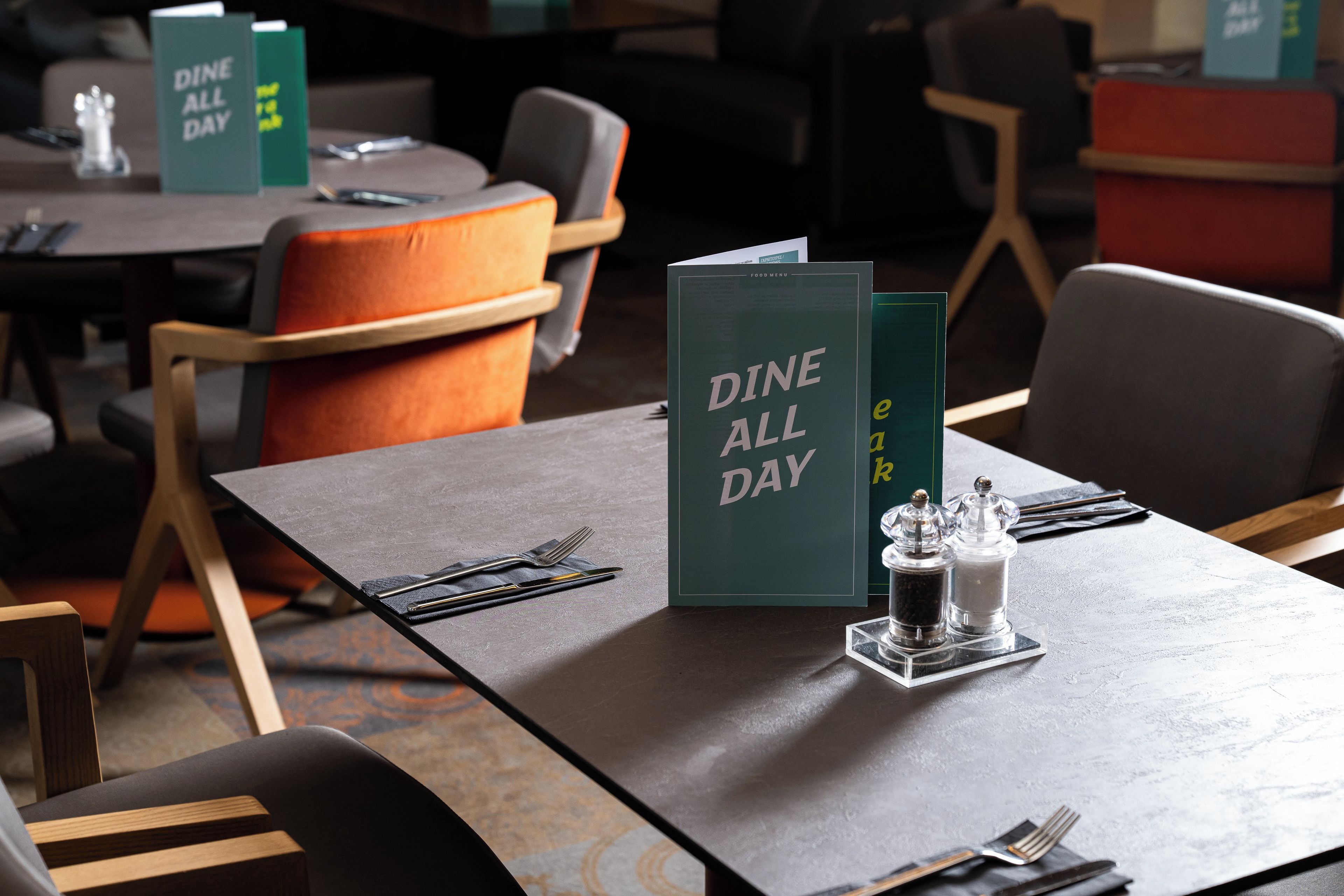 A restaurant setting with tables set for dining, including menus and condiments.