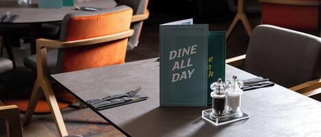 A restaurant setting with tables set for dining, including menus and condiments.