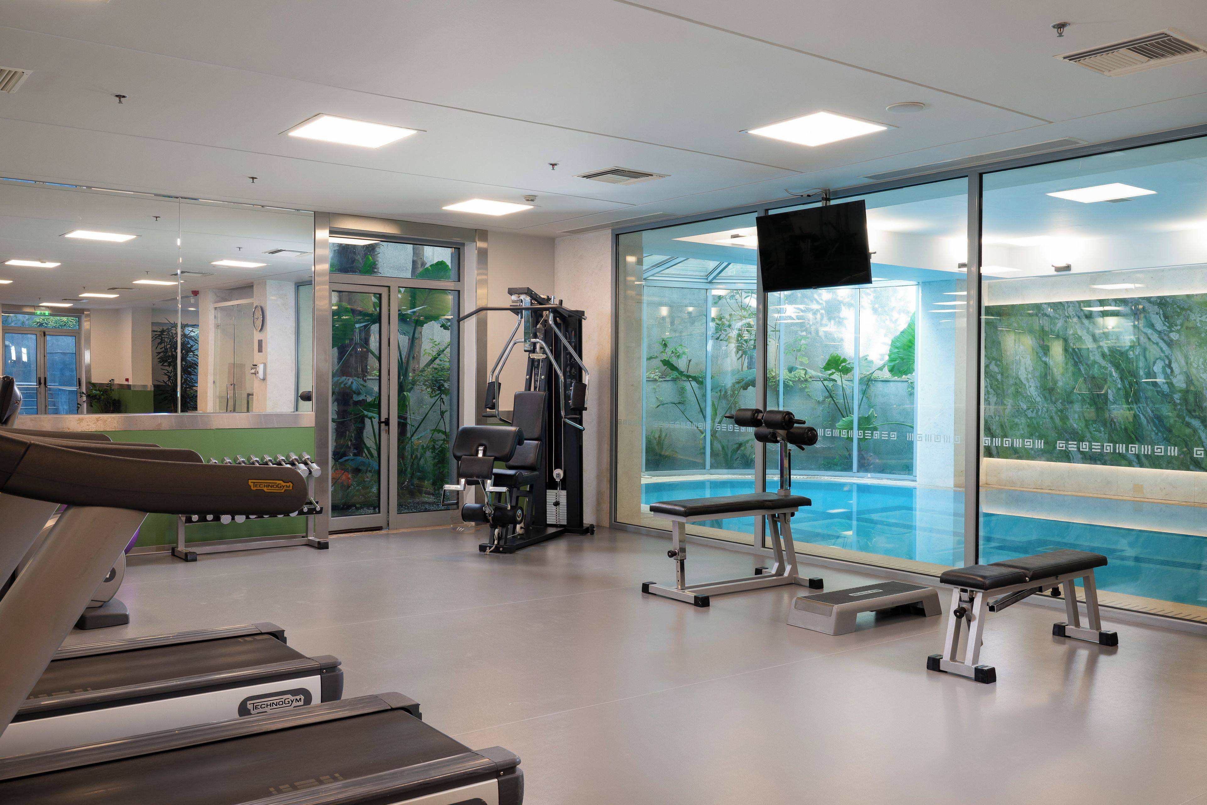 Una palestra con tapis roulant, macchinari per pesi e una panca.