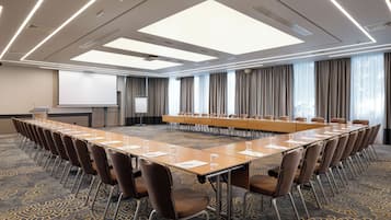 A conference room with a long table, chairs, a projector screen, and a carpeted floor.