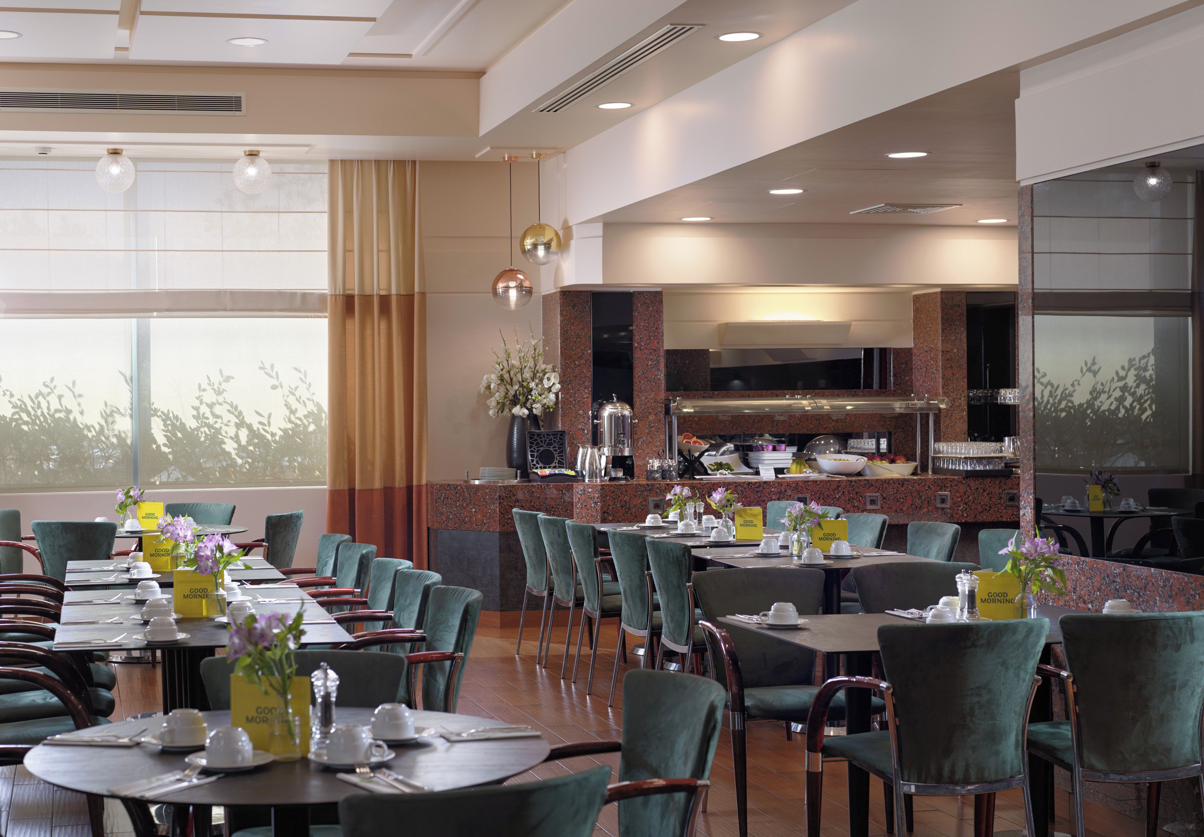 A restaurant with multiple dining tables and chairs, a kitchen area, and large windows.