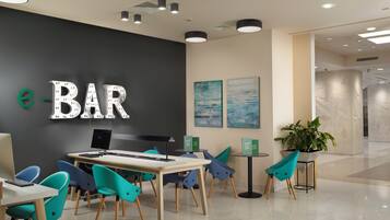 A modern bar area with a black wall, teal chairs, and a wooden table.