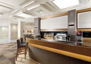 Un área de bar moderna con una barra curva, asientos y una máquina de café.