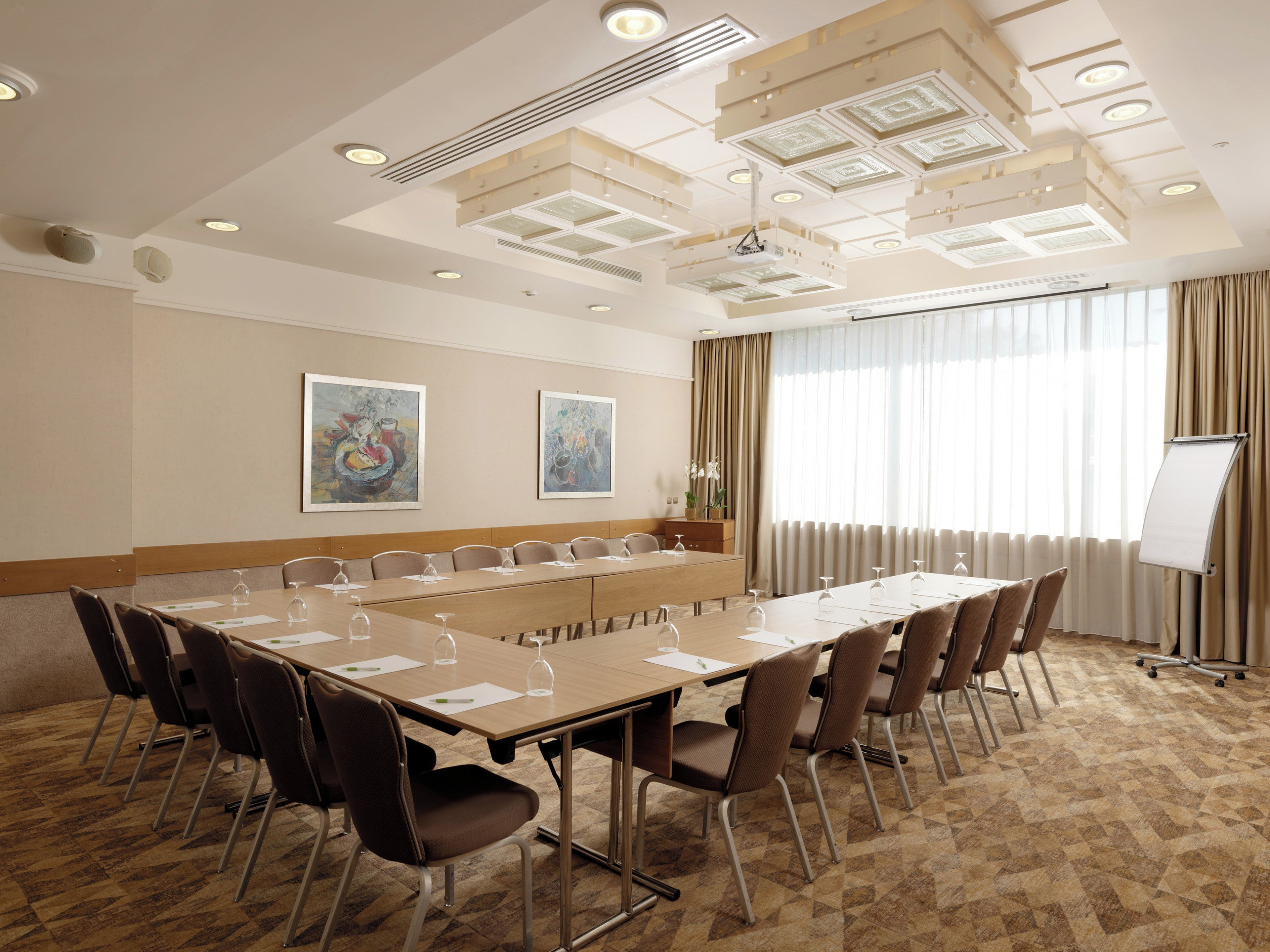 A conference room with a long table, chairs, a whiteboard, and artwork on the walls.