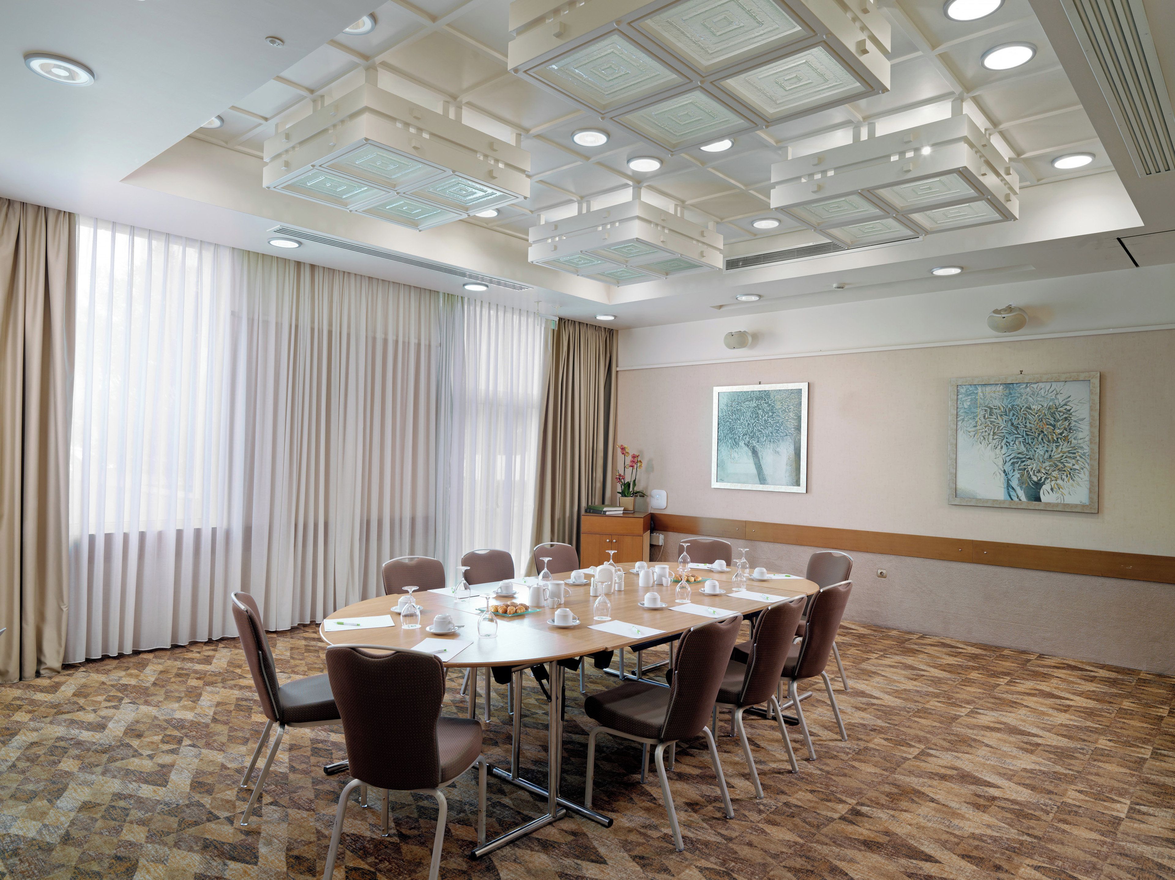 A conference room with a large table, chairs, and a ceiling with recessed lighting.