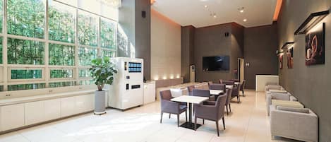 A modern restaurant with a large window, a coffee machine, and a flat-screen TV.