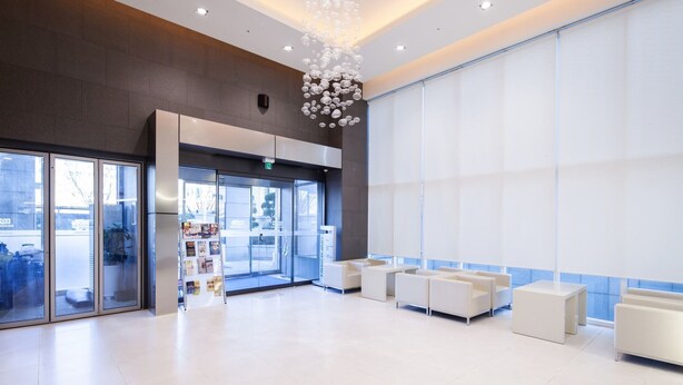 A modern lobby with a reception desk, seating area, and a large window. - Uljiro Co-Op Residence (Seoul)